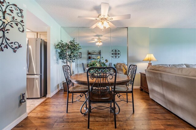 dining area featuring baseboards, a textured ceiling, a ceiling fan, and wood finished floors