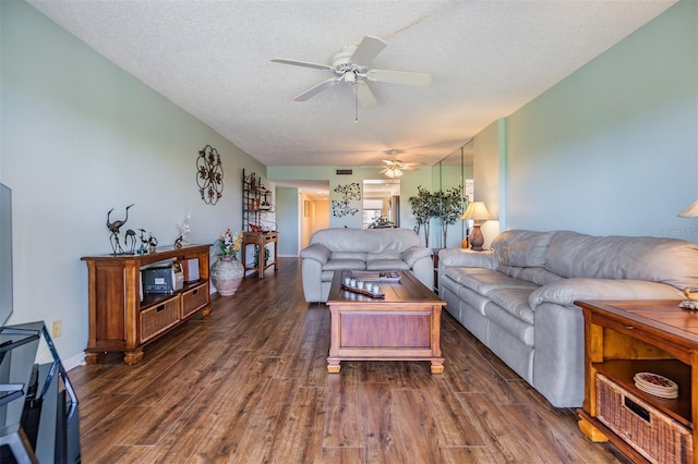 living area with dark wood-type flooring, a ceiling fan, baseboards, and a textured ceiling