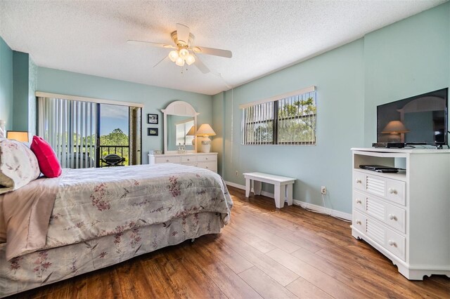 bedroom featuring access to exterior, a textured ceiling, wood finished floors, baseboards, and ceiling fan