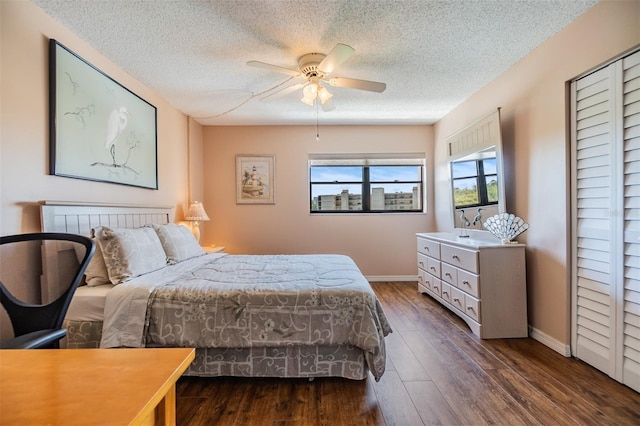 bedroom with a ceiling fan, wood finished floors, baseboards, and a textured ceiling