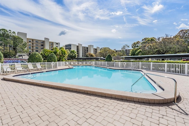 community pool with a patio and fence