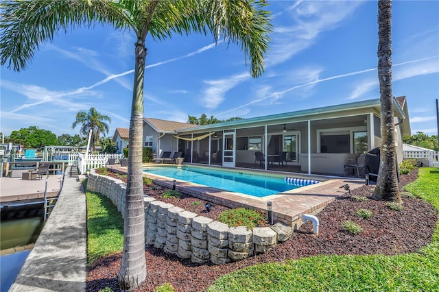 pool featuring a patio, fence, a boat dock, and a sunroom