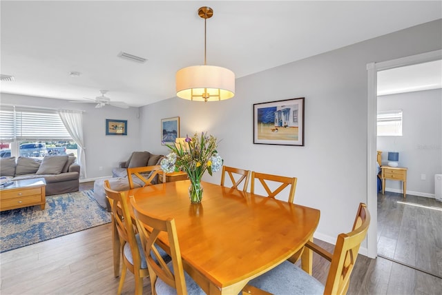 dining space with ceiling fan, wood finished floors, visible vents, and baseboards