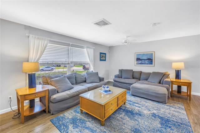 living area with a ceiling fan, wood finished floors, visible vents, and baseboards