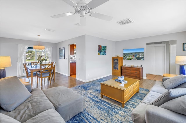 living room with visible vents, baseboards, ceiling fan, and wood finished floors