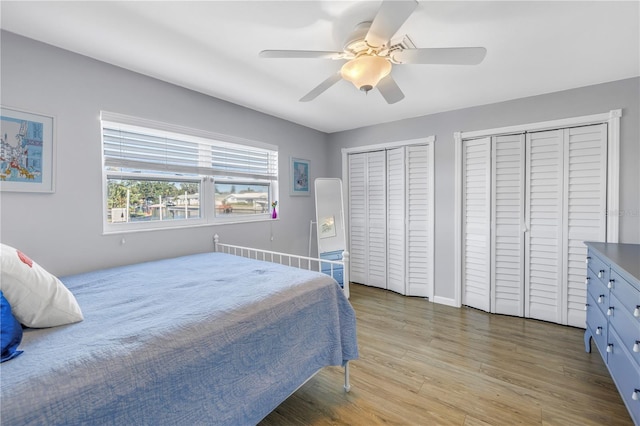bedroom featuring ceiling fan, two closets, and wood finished floors