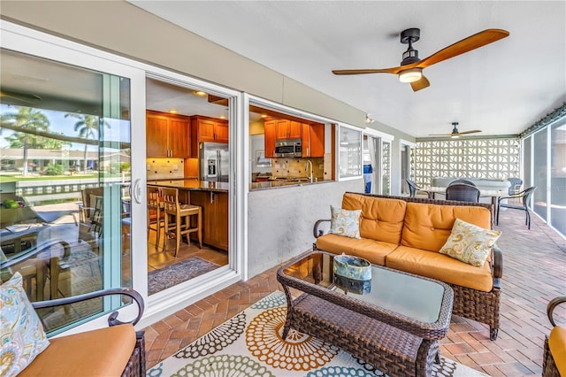 sunroom / solarium with an outdoor living space, outdoor dining area, a ceiling fan, and a sink