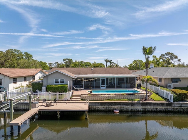 rear view of house with a water view, a fenced backyard, and a sunroom