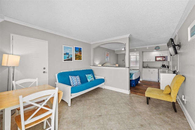 living room featuring crown molding, light tile patterned floors, baseboards, and a textured ceiling