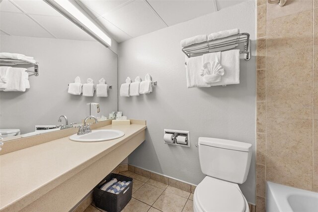 full bath with a sink, baseboards, toilet, and tile patterned flooring