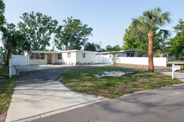 view of front facade with driveway, stucco siding, and fence