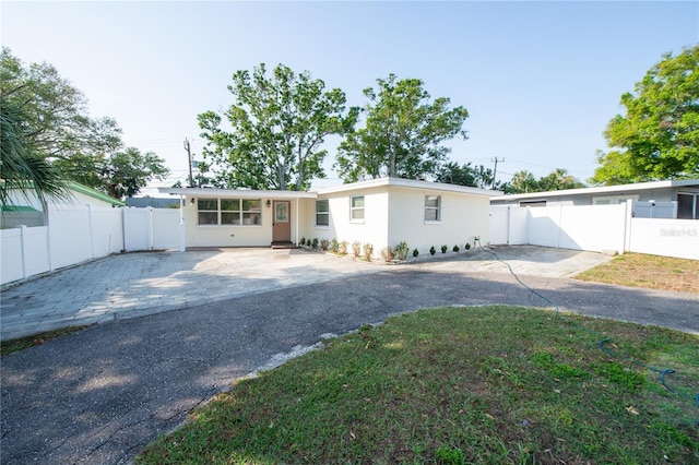 single story home featuring driveway, a patio area, stucco siding, fence, and a front lawn