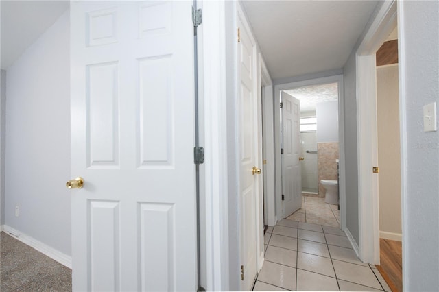 hallway with light tile patterned flooring and baseboards