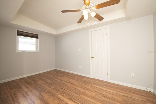 unfurnished room featuring baseboards, wood finished floors, and a raised ceiling