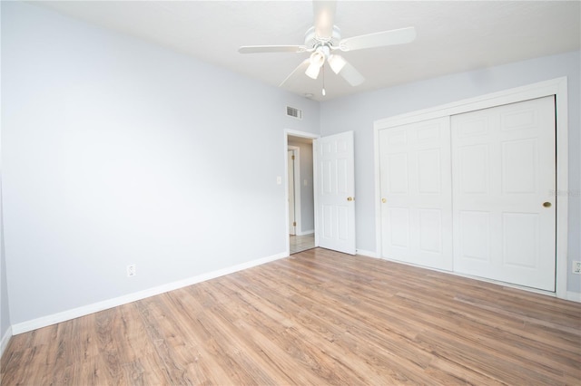 unfurnished bedroom featuring baseboards, light wood finished floors, ceiling fan, visible vents, and a closet