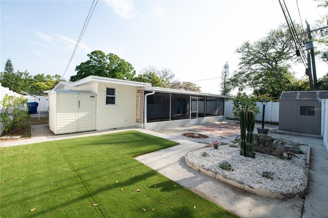 rear view of property featuring an outdoor structure, a sunroom, fence, a yard, and a storage shed