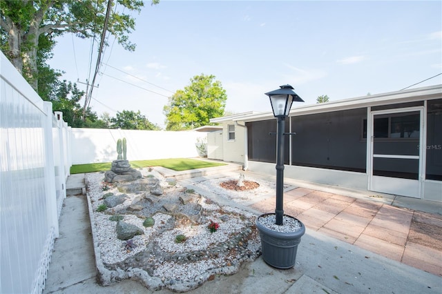 view of yard featuring a patio, a sunroom, and a fenced backyard