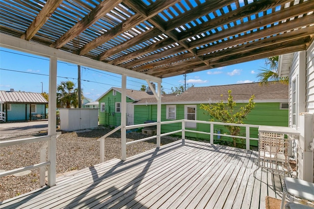 wooden deck featuring a pergola, a shed, and an outbuilding