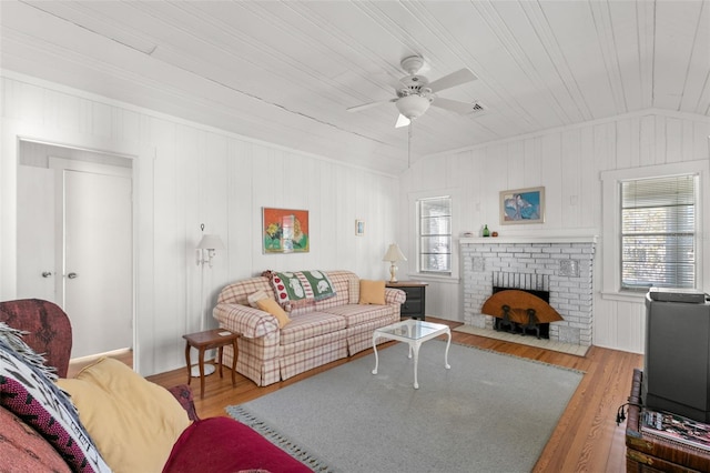 living area with a fireplace, wood finished floors, vaulted ceiling, and ceiling fan