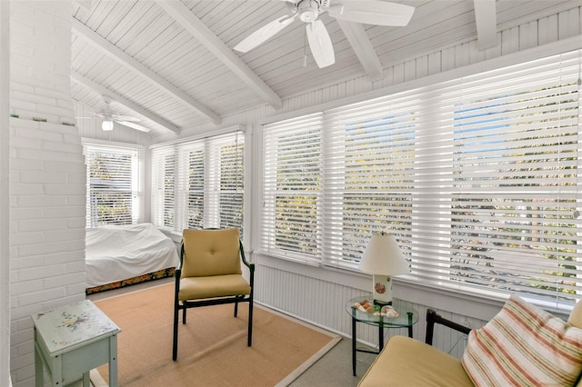 sitting room with a ceiling fan, vaulted ceiling with beams, and brick wall