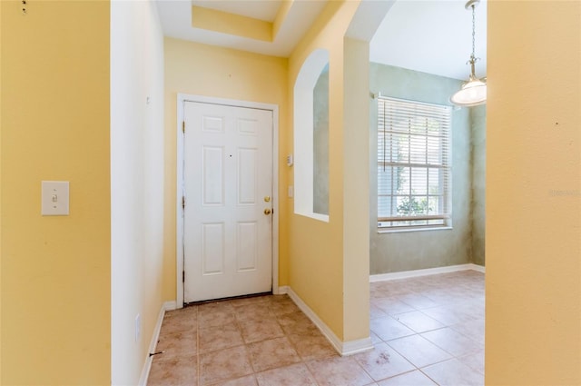 interior space with light tile patterned flooring, baseboards, and arched walkways