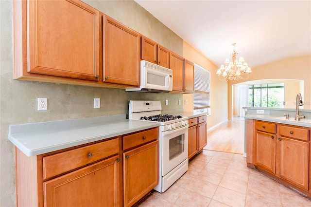 kitchen with an inviting chandelier, light countertops, pendant lighting, and white appliances