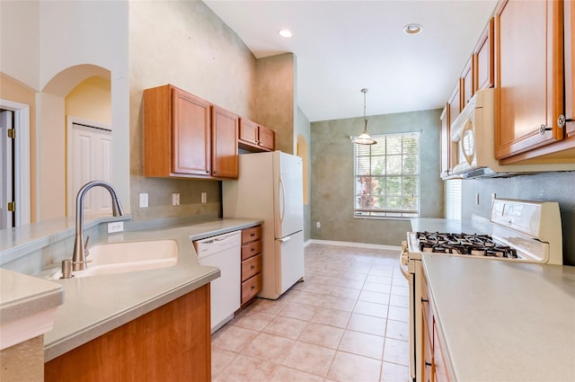 kitchen featuring light countertops, white appliances, a sink, hanging light fixtures, and brown cabinetry