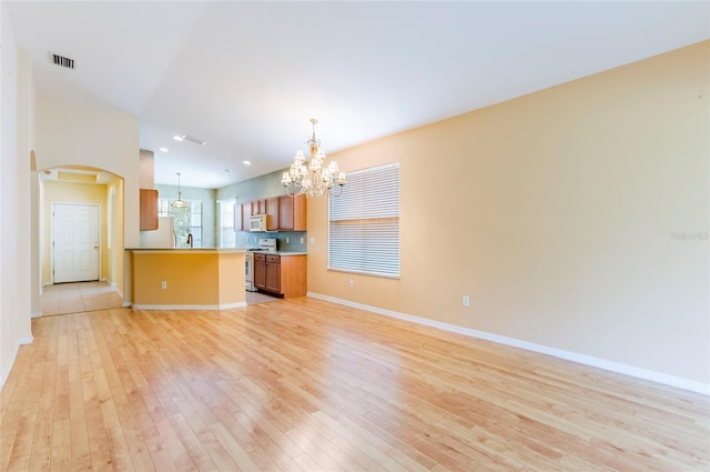 kitchen with visible vents, white appliances, light wood-type flooring, open floor plan, and a notable chandelier
