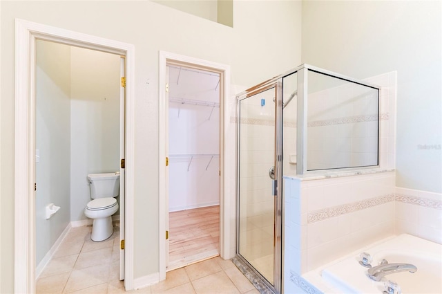 bathroom with tile patterned floors, a walk in closet, a stall shower, and a bath