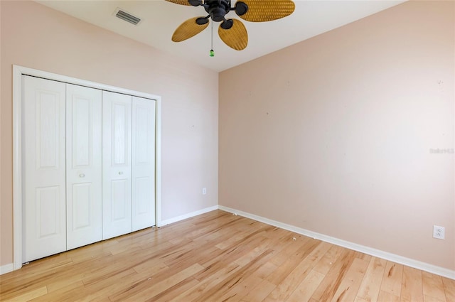 unfurnished bedroom with a closet, a ceiling fan, light wood finished floors, baseboards, and visible vents