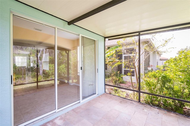 unfurnished sunroom featuring beam ceiling
