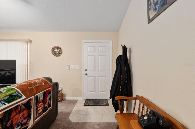 foyer featuring tile patterned floors, carpet, and baseboards