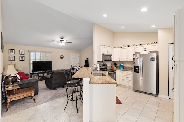kitchen featuring light stone countertops, a peninsula, stainless steel appliances, a kitchen breakfast bar, and open floor plan