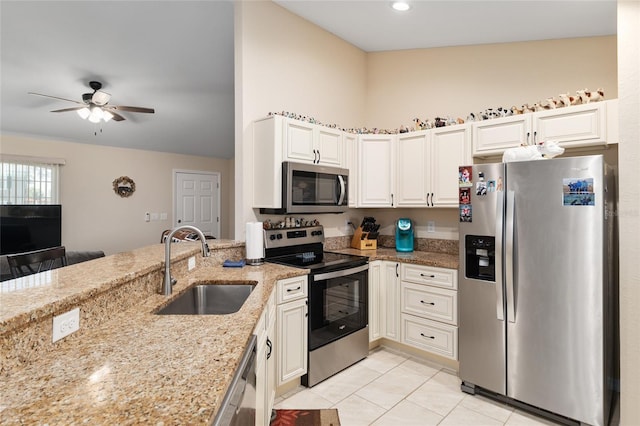 kitchen with ceiling fan, light stone countertops, a peninsula, appliances with stainless steel finishes, and a sink