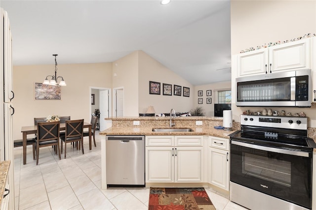 kitchen featuring lofted ceiling, appliances with stainless steel finishes, a peninsula, an inviting chandelier, and a sink