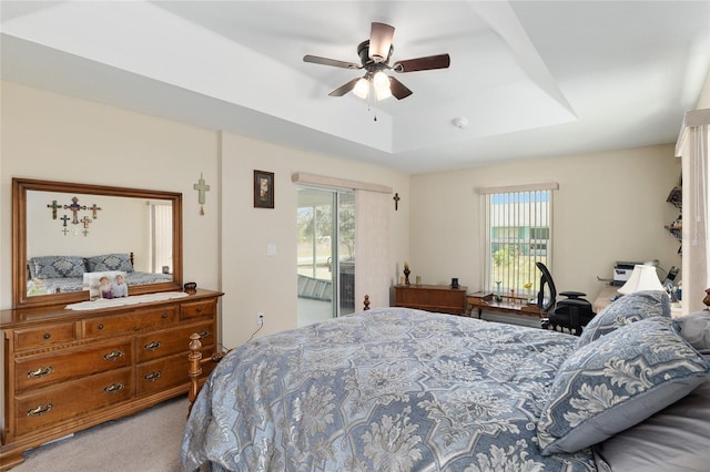 bedroom with a tray ceiling, access to outside, carpet floors, and ceiling fan