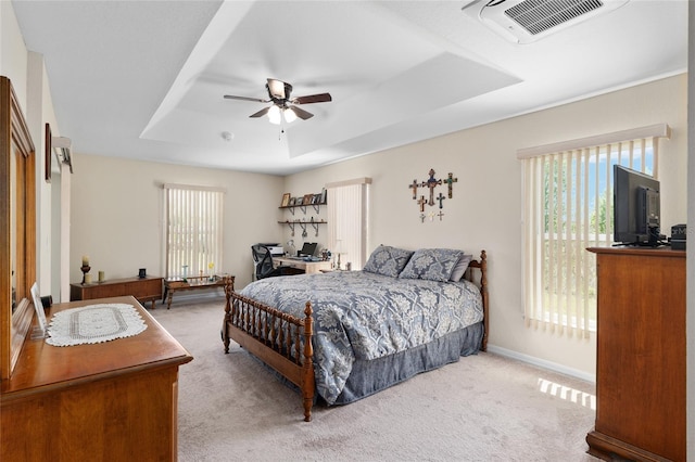 carpeted bedroom with baseboards, visible vents, a ceiling fan, and a tray ceiling