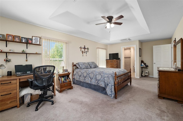 bedroom featuring visible vents, carpet flooring, ensuite bathroom, a raised ceiling, and a ceiling fan