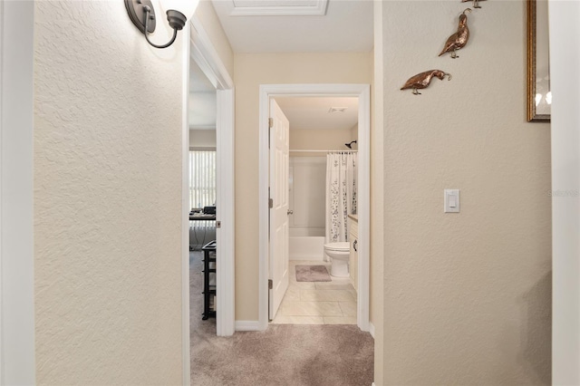 hall with a textured wall, baseboards, and carpet floors