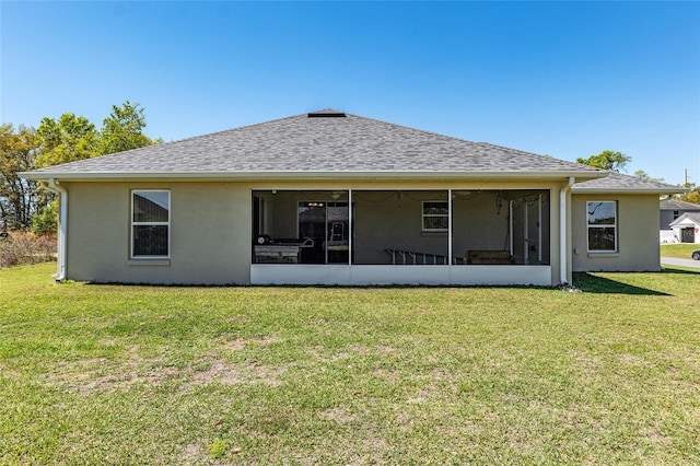 rear view of property featuring stucco siding, roof with shingles, a yard, and a sunroom