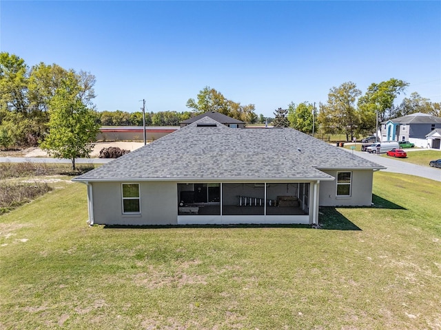 rear view of property featuring stucco siding, a lawn, and a shingled roof
