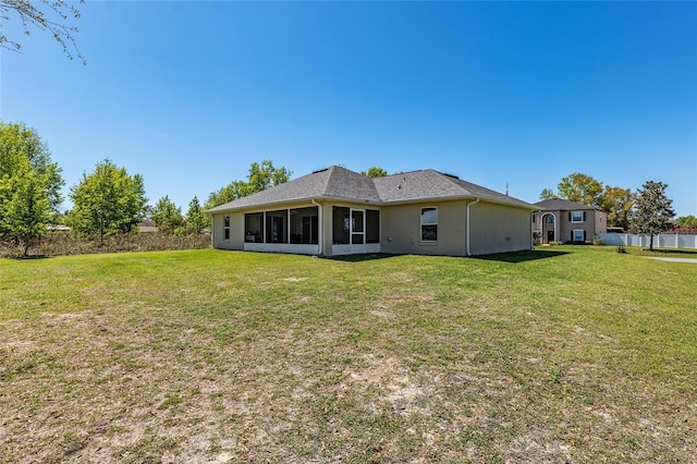 back of property with stucco siding, fence, a yard, and a sunroom