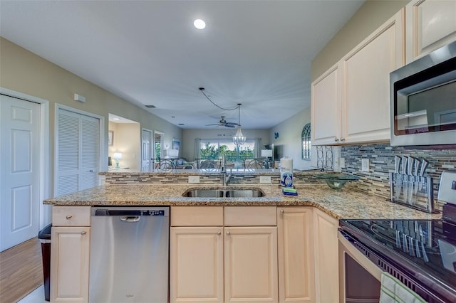 19829 Gulf Blvd Unit 601, Indian Shores, FL 33785 - kitchen featuring light stone counters, a peninsula, a sink, appliances with stainless steel finishes, and open floor plan