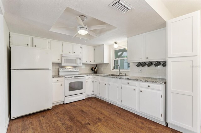 kitchen featuring visible vents, a sink, white appliances, white cabinetry, and dark wood-style flooring