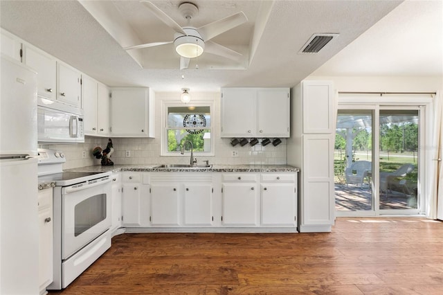 kitchen featuring white appliances, visible vents, a tray ceiling, a sink, and dark wood-type flooring