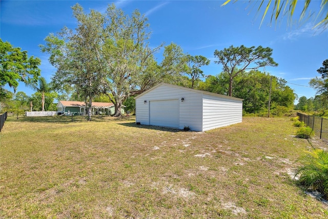 view of yard with a detached garage, an outbuilding, and fence