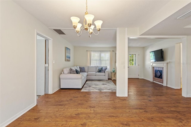 living room with a fireplace, wood finished floors, visible vents, and a chandelier