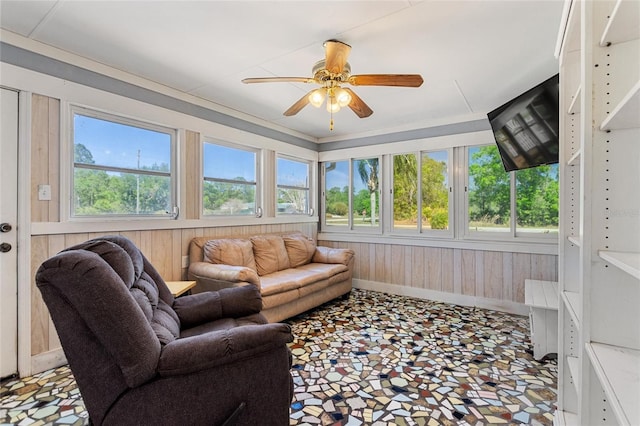 sunroom featuring wood walls, an outdoor hangout area, and ceiling fan
