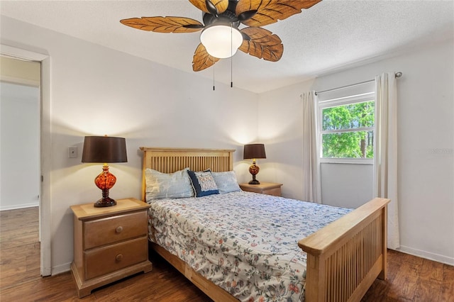 bedroom featuring ceiling fan, wood finished floors, baseboards, and a textured ceiling