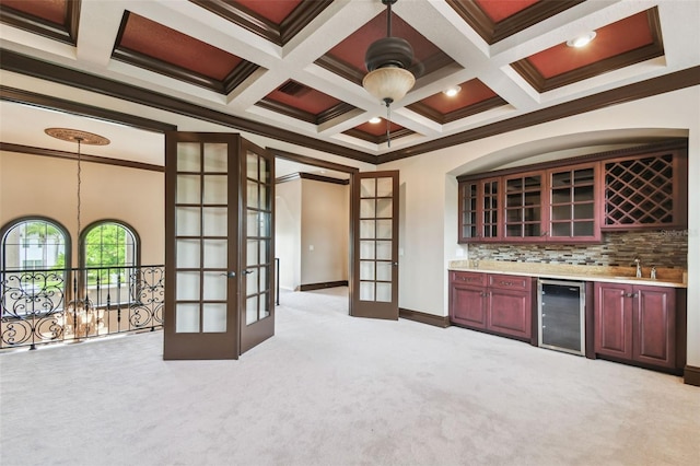 bar with beverage cooler, coffered ceiling, wet bar, french doors, and light colored carpet